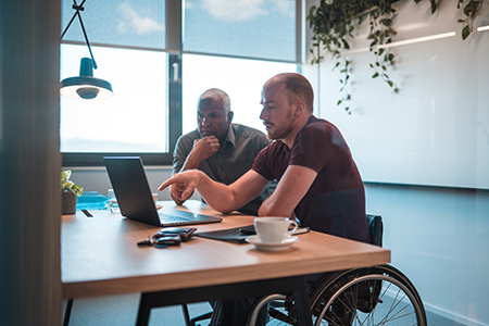 Man on wheelchair presenting on a laptop to a client